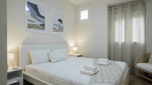 A hotel room with a bed, two bedside tables, a chair, and artwork on the walls. - Private Jacuzzi Apartment in Central Seville – 4 Guests (Sevilla)