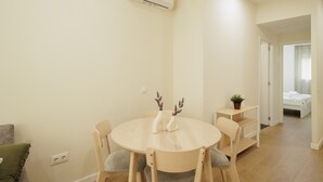 A modern, well-lit room with a round dining table, chairs, and a small plant on a side table. - Private Jacuzzi Apartment in Central Seville – 4 Guests (Sevilla)