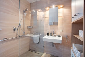A modern bathroom with a glass shower enclosure, a white sink, and a mirror above it.