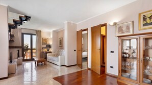 Uma sala de estar ampla com piso de madeira, um sofá, uma mesa de centro e um armário com copos.