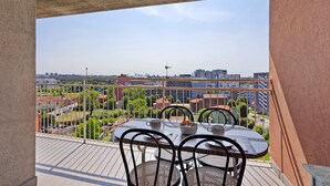 Varanda com mesa e cadeiras, proporcionando vista para o horizonte urbano com edifícios e áreas verdes.