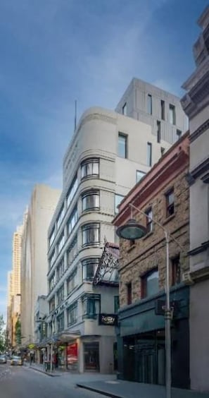 Un edificio de varios pisos con fachada curva, ventanas amplias y entrada a nivel de calle.