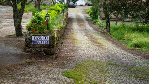 Ein Kopfsteinpflasterweg führt zu einem Steinschild mit der Aufschrift 'Casa do Mogadouro'.
