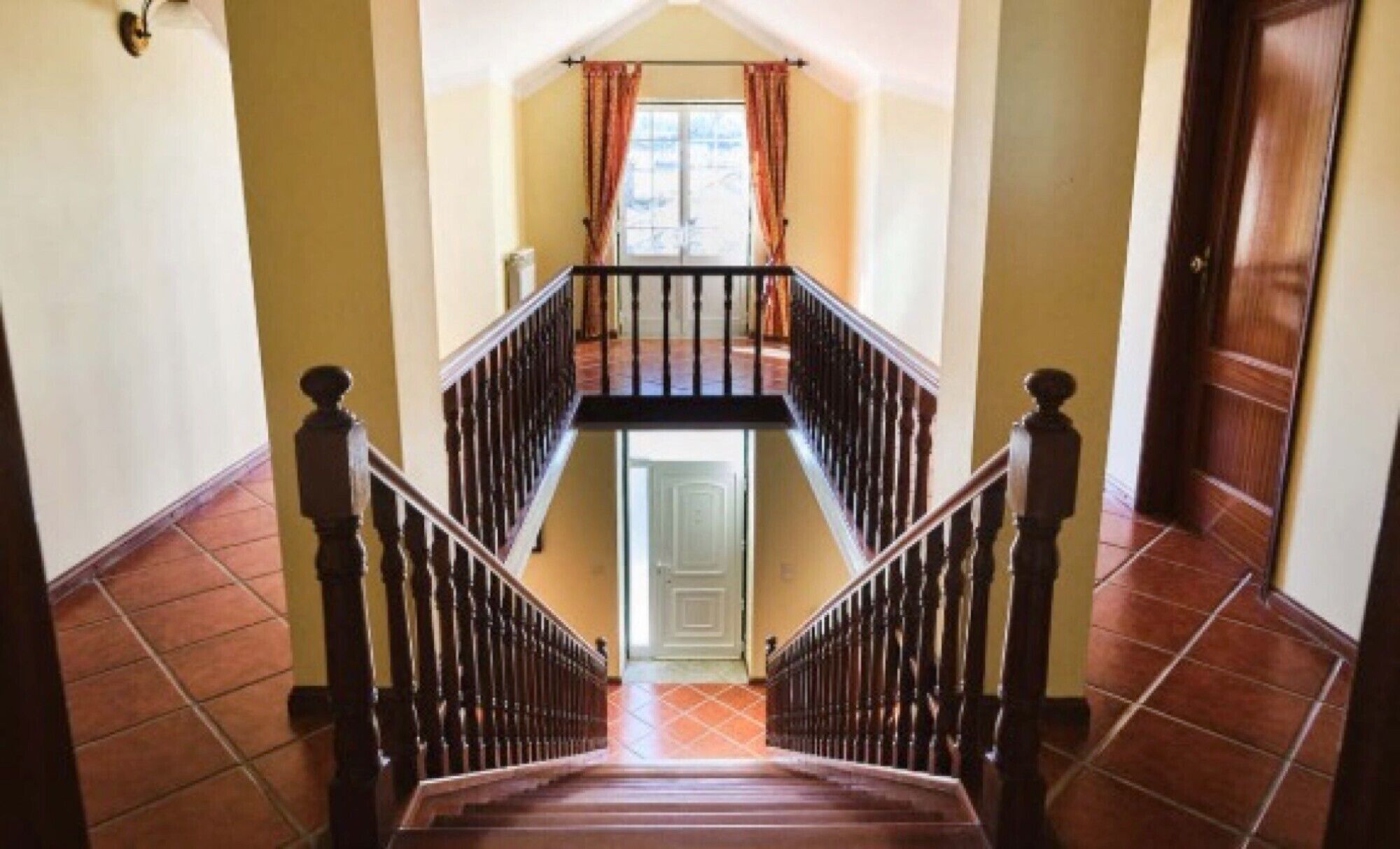 Eine Treppe mit einem Holzgeländer und Blick auf eine Tür am Fuß.