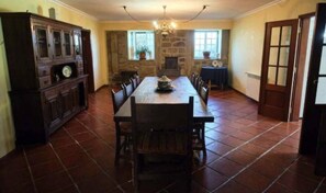 A dining area with a long wooden table, stone walls, and a chandelier.