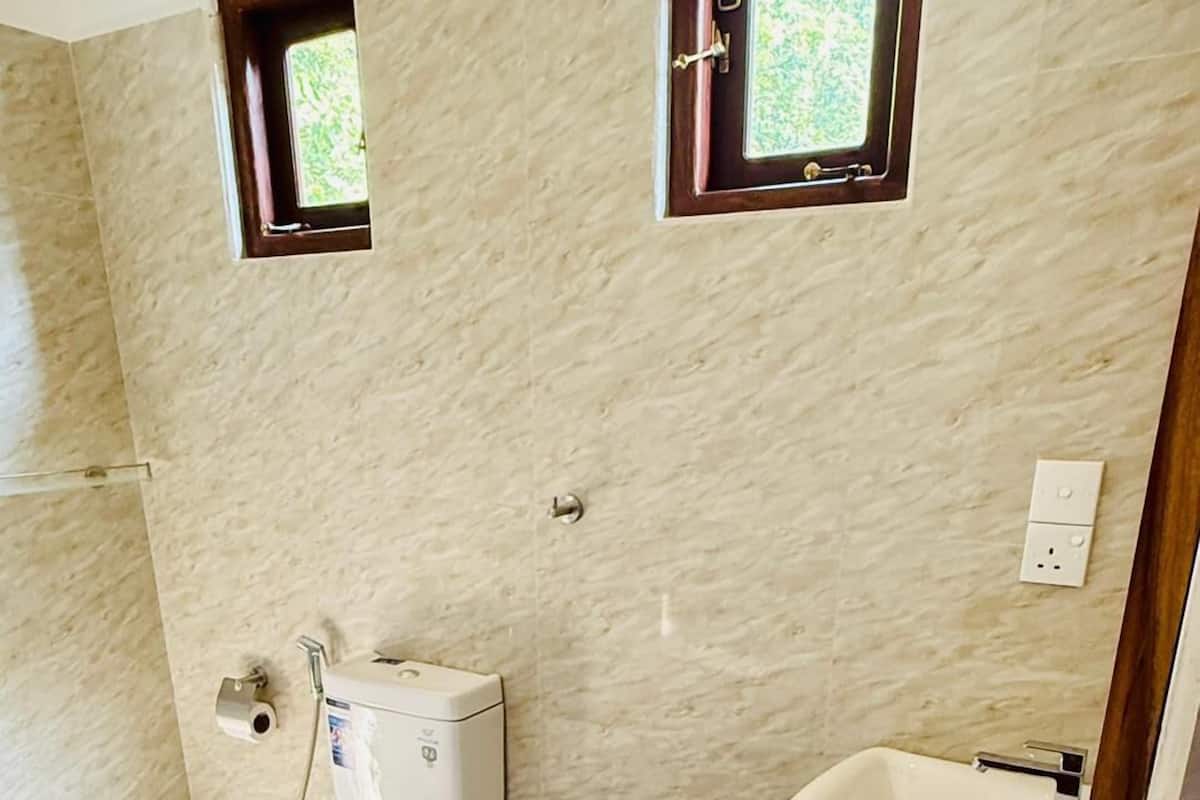 Ein Badezimmer mit Toilette, Waschbecken und zwei kleinen Fenstern.