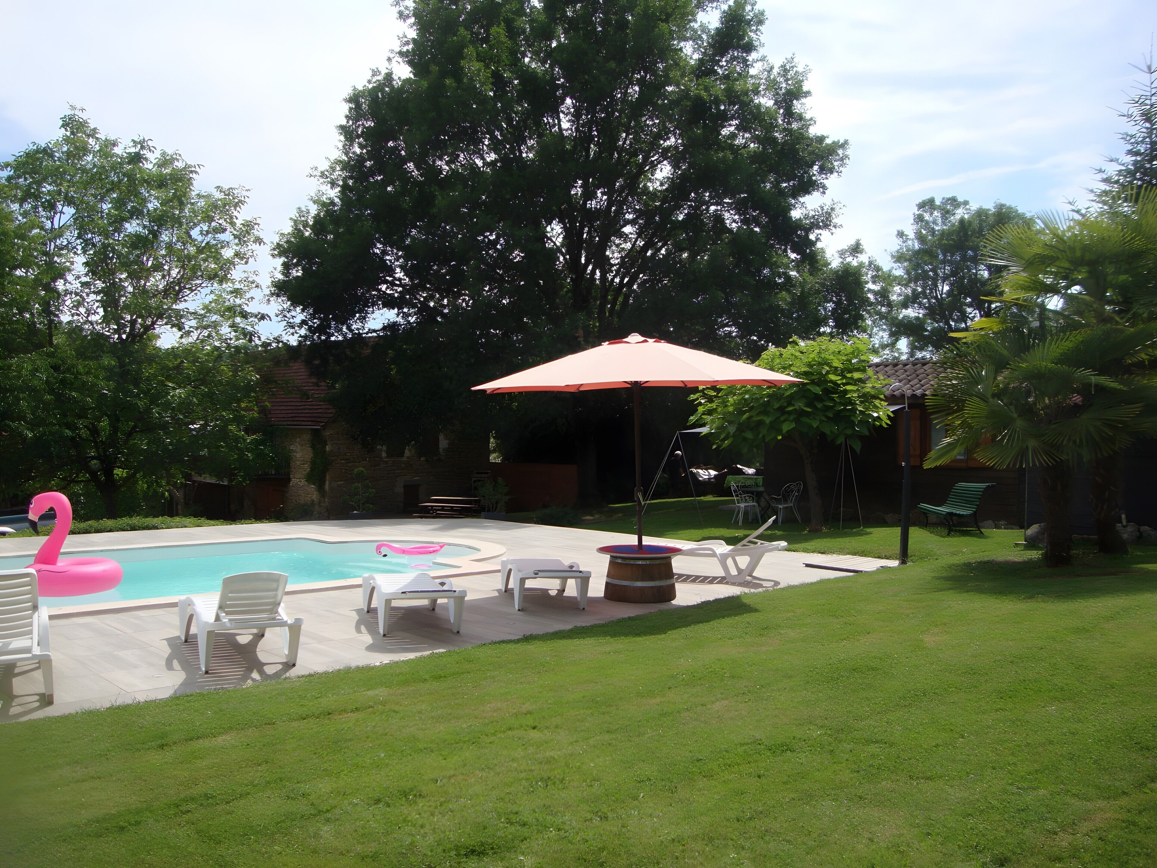 Un jardin avec une piscine, des chaises longues et un flotteur en forme de flamant rose.