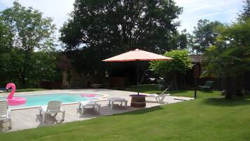 Un jardin avec une piscine, des chaises longues et un flotteur en forme de flamant rose.