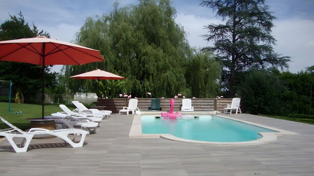 A swimming pool with lounge chairs and umbrellas, surrounded by greenery. - Holiday Home “Gîte Le Séchoir” with Shared Pool, Wi-Fi and Air Conditioning (Le Vignon-en-Quercy)
