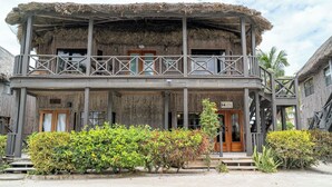 Un edificio di legno a due piani con un balcone, un tetto di paglia e un portico in legno.