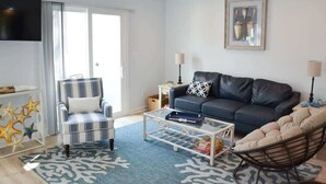 A modern living room with a sofa, armchair, coffee table, and a television. - Waterfront Coastal Escape (Atlantic Beach)