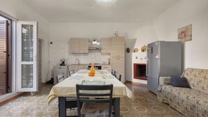 Uma cozinha compacta com mesa de jantar, cadeiras, sofá e geladeira.
