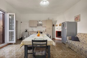 A compact kitchen with a dining table, chairs, a sofa, and a refrigerator. - Casa Mare Blu by BarbarHouse (San Pietro in Bevagna)