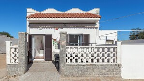Uma casa de dois andares com telhado em telhas, varanda e portão.