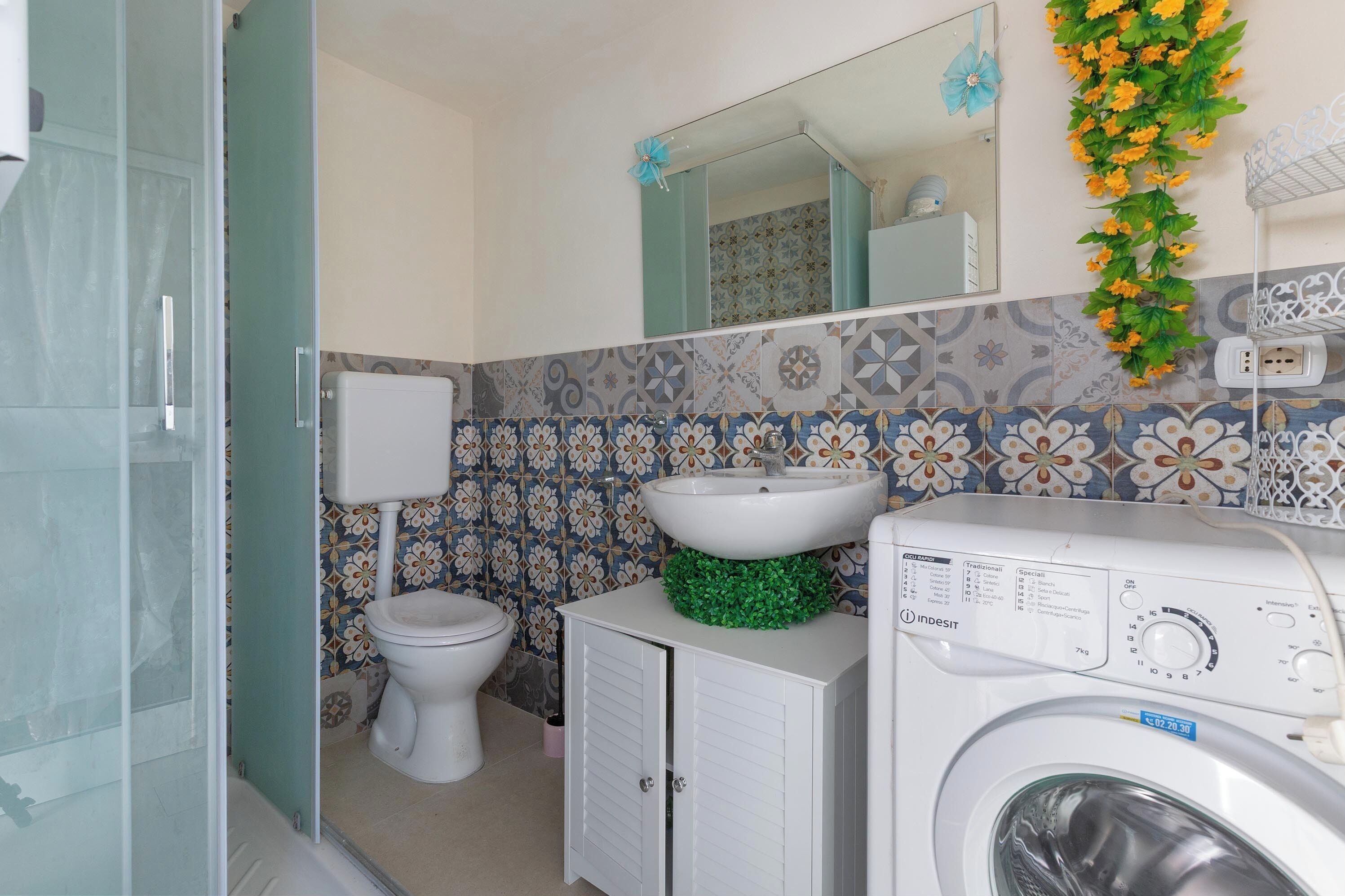 Un baño con inodoro, lavabo, lavadora y zona de ducha.