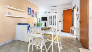 Un comedor con una mesa, sillas, un armario blanco y un televisor.