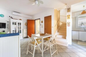 A kitchen with white cabinets, a dining table with chairs, a staircase, and a ceiling fan. - Gelso Selvatico by BarbarHouse (Carovigno)