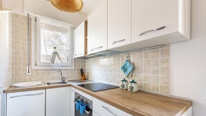 Una cocina moderna con armarios blancos, encimera de madera, ventana con vistas y una toalla colgando.