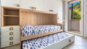 Un dormitorio con cama, almacenamiento integrado y puerta corrediza de vidrio a un balcón.