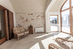 Una habitación con pared de piedra, un sofá, una mesa y un ventanal grande.