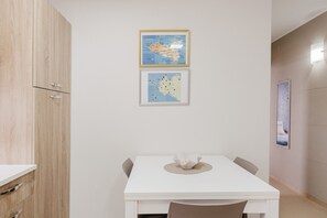 A dining area with a white table, two chairs, a framed map, and a cabinet.