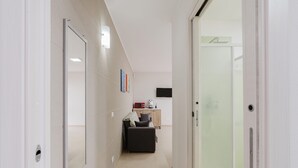 Un pasillo con un sofá, microondas y una puerta de ducha de vidrio.