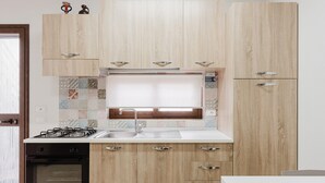 Una cocina con armarios de madera, estufa a gas, lavavajillas y ventana sobre el fregadero.