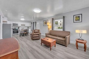 Un salon moderne comprenant un canapé, un fauteuil, une table basse et un coin repas avec des chaises et une table.