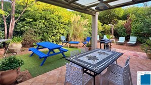 Un'area patio coperta con tavolo da picnic, sedie blu e un tavolino decorato con motivo geometrico.