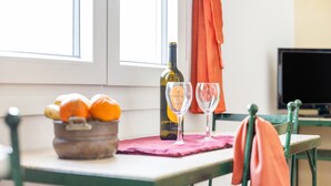 A dining table with a bottle of wine, two glasses, and a bowl of fruit. - Portón 1 Studio – Renovated with Sea Views (Conil de la Frontera)