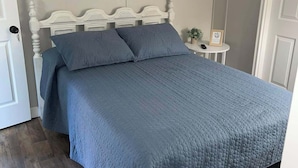 A bedroom with a bed, a nightstand, and a door.