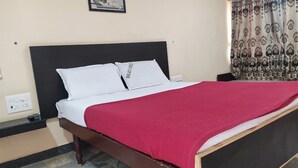 Una cama con cabecera negra, ropa de cama blanca y una manta roja.