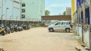 Un estacionamiento con una fila de motocicletas estacionadas y un SUV plateado.