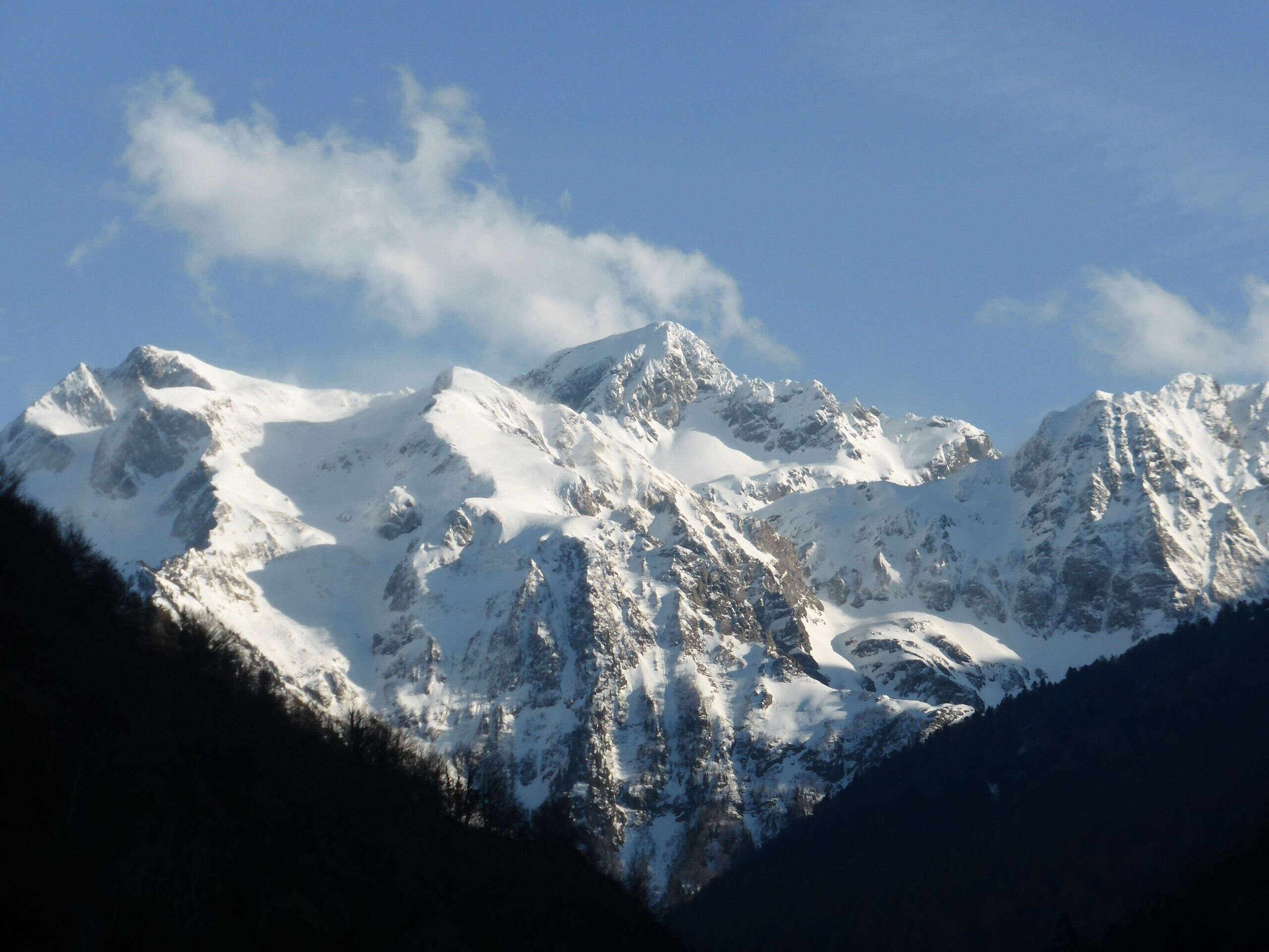 A snow-covered mountain range with rugged peaks and a clear sky.