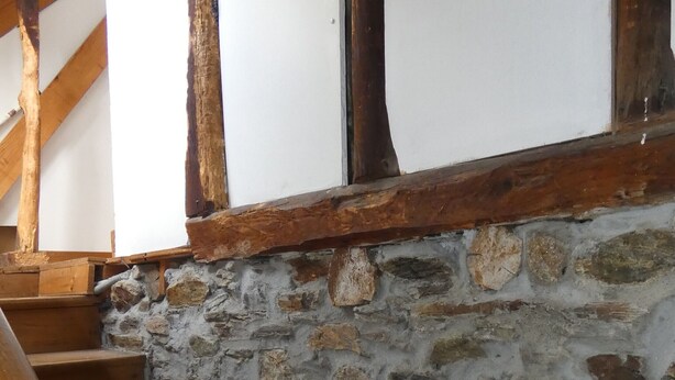 Eine Treppe mit Holzdielen und einer Steinsäule.