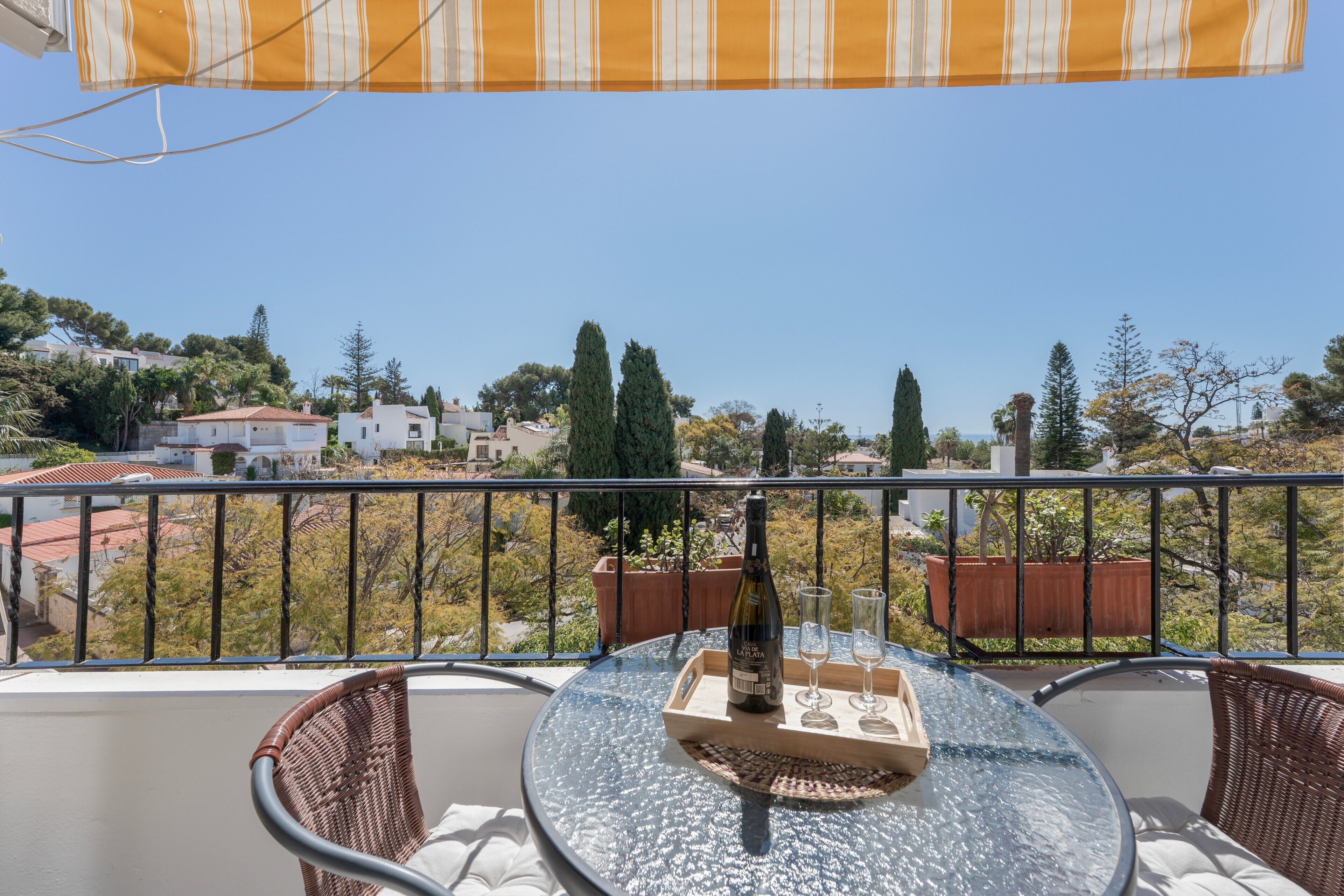 Ein Balkon mit Tisch, Stühlen, einer Flasche und Gläsern.