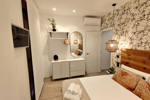 Ein Schlafzimmer mit einem Bett, einer Kommode, einem Spiegel, einem an der Wand montierten Fernseher und einem Deckenventilator.