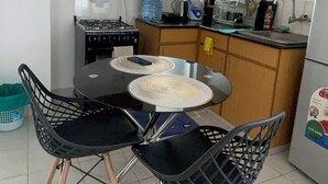 Ett kök med träskåp, en gasspis, ett handfat och ett matbord med stolar.