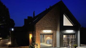 Una casa moderna con techo inclinado, un amplio acceso por puerta de vidrio y un interior bien iluminado.