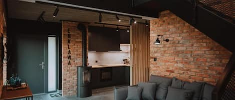Un interior moderno con pared de ladrillo, un sofá, una zona de cocina y una escalera.