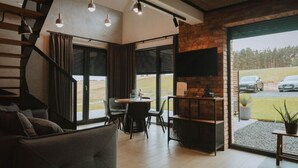 Interior moderno com escada, área de refeições e janelas amplas com vista para o exterior.