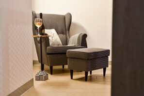 A modern room with a grey upholstered armchair, a matching ottoman, a small side table with a wine glass and bottle, and a patterned floor lamp. - Large Holiday Home With a Jacuzzi on the Terrace (Koscierzyna)
