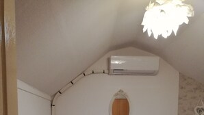 A bedroom with a bed, a small window, an air conditioning unit, and a radiator. - LE GITE DU CHATEAU NEAR MARAIS POITEVIN (Fors)