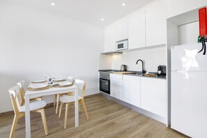 Una cocina moderna con armarios blancos, horno empotrado y refrigerador.