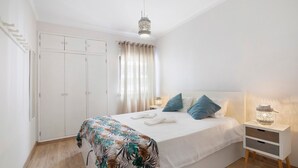 Una camera da letto con un letto, un comodino, una lampada, un armadio e una finestra con tende.