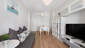 Un soggiorno moderno con divano, televisore, tavolo da pranzo e lampadario.