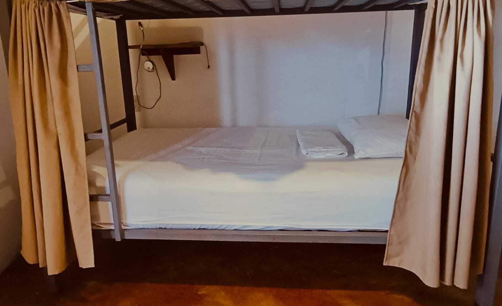 A bunk bed with a headboard, a small shelf, and a curtain.