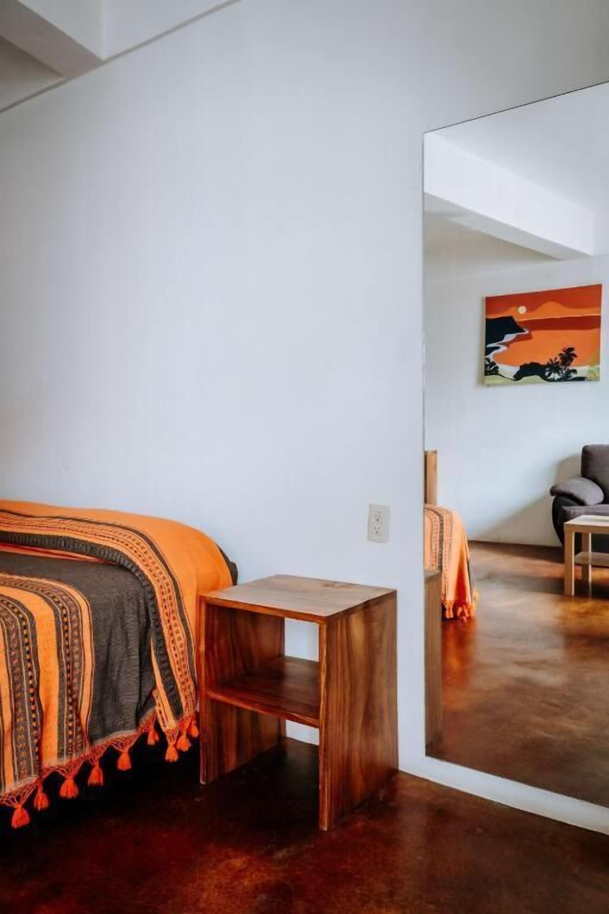 Une chambre à coucher avec un lit, une petite table en bois et un tableau accroché au mur.