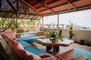 Une terrasse sur le toit, aménagée avec un hamac, un coin salon et des plantes en pot.