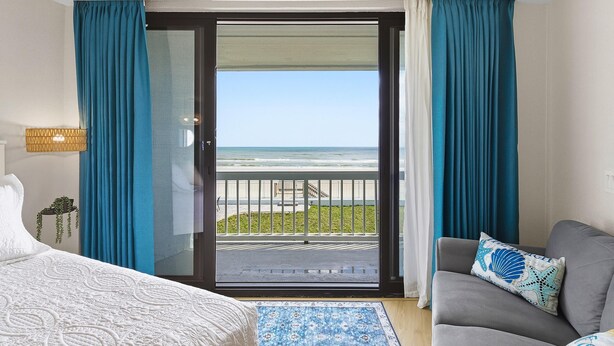 Ein Hotelzimmer mit Balkon, einem Bett, einer Couch und Meerblick.